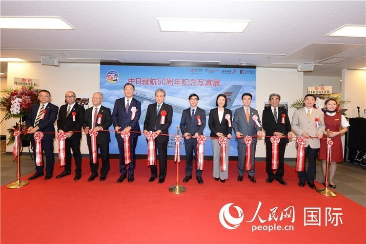與會(huì)嘉賓共同為中日通航50周年紀(jì)念圖片展開幕剪彩。馮學(xué)敏攝