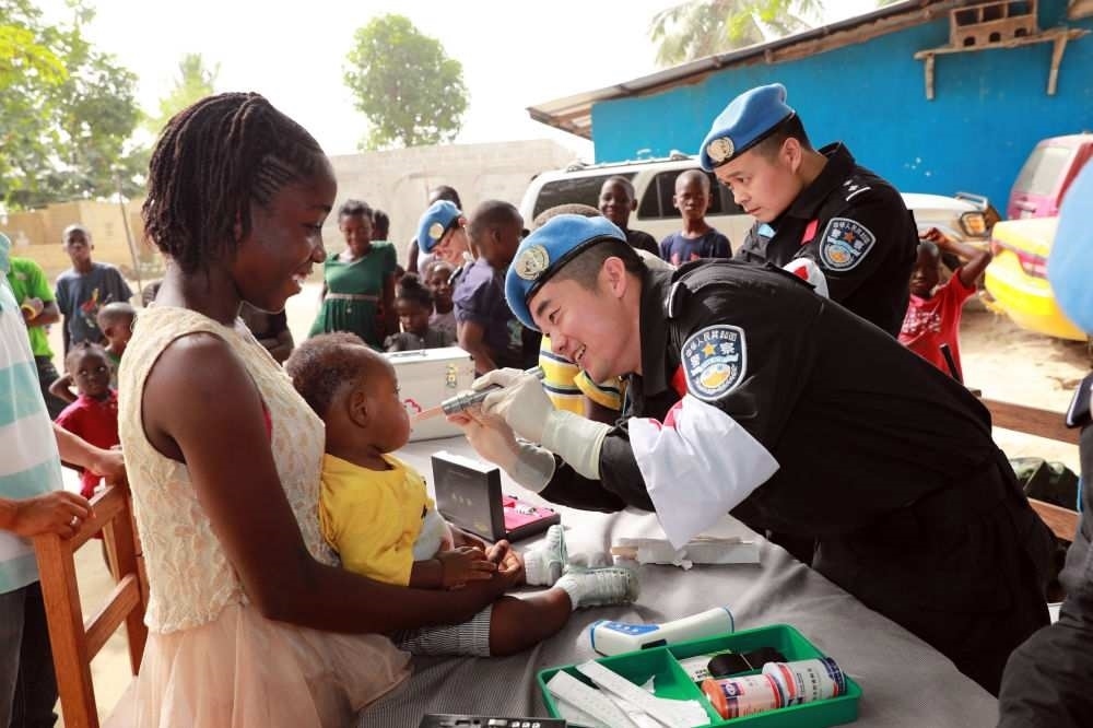 2017年12月28日，在利比里亞蒙羅維亞，中國維和警察防暴隊醫(yī)療人員為兒童做口腔檢查。