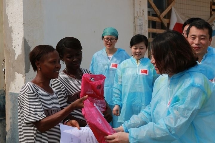 2015年4月4日，在位于塞拉利昂首都弗里敦市郊的中塞友好醫(yī)院埃博拉診療中心，中國(guó)第四批援塞醫(yī)療隊(duì)副隊(duì)長(zhǎng)邵蔚（右前）向被治愈的埃博拉出血熱患者贈(zèng)送禮物。新華社發(fā)（祖榮強(qiáng) 攝）