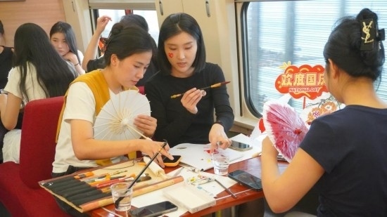 10月1日，旅客們在G1634次列車上給油紙傘作畫。新華社記者周義 攝