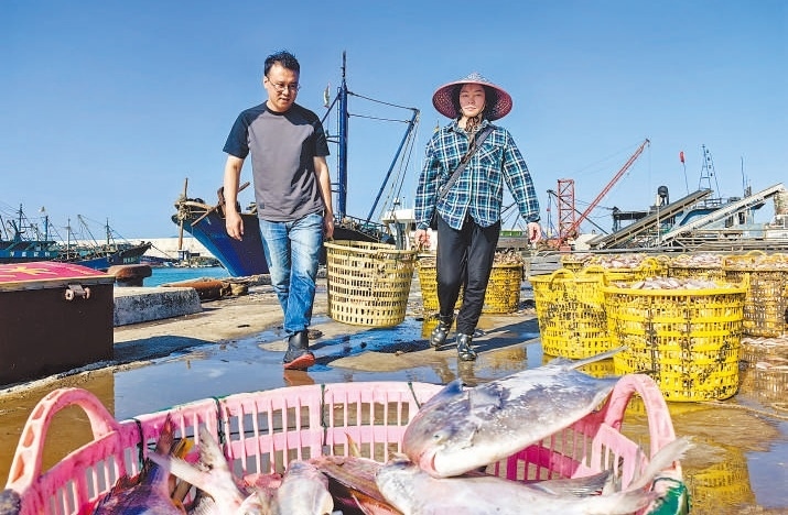 許小斌（左）和漁民一起搬運(yùn)海鮮。本報(bào)記者 付 文攝