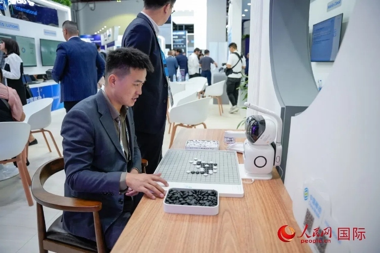 觀眾在中國移動國際有限公司展臺體驗智慧圍棋機器人。人民網(wǎng) 塔里克·易卜拉欣攝