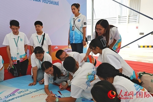 泰國(guó)學(xué)生在開營(yíng)儀式展板上繪制圖案。人民網(wǎng)記者 白元琪攝