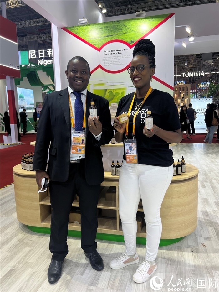 6月6日，布隆迪駐華大使館一等參贊布利馬索·阿爾弗雷德 (左，Bulimaso Alfred) 和參展商卡馬里扎·埃斯特拉 (Kamariza Estella) 在第七屆中國國際進(jìn)口博覽會(huì)布隆迪館展示當(dāng)?shù)厣a(chǎn)的辣木油。（人民網(wǎng) 艾里士 攝）
