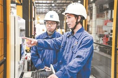 在廣西柳工機(jī)械股份有限公司生產(chǎn)車(chē)間內(nèi)，一名高級(jí)技師（右）給徒弟講解數(shù)控設(shè)備操作細(xì)節(jié)。新華社記者 曹祎銘攝