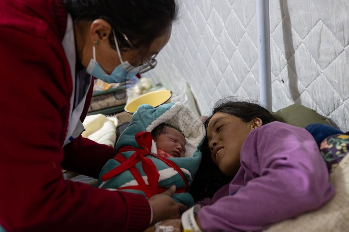 1月10日，定日縣中心醫(yī)院的婦產(chǎn)科醫(yī)生悉心照看一位母親和她懷里的新生兒。人民日?qǐng)?bào)記者張武軍攝