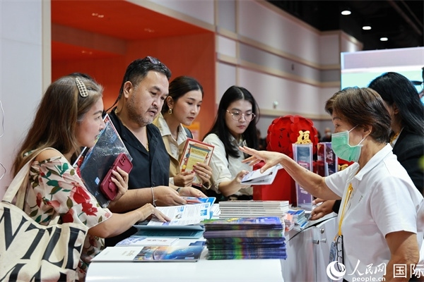 外國(guó)觀眾在中國(guó)展臺(tái)仔細(xì)閱讀赴華旅游介紹，向工作人員咨詢關(guān)于中國(guó)美食和景點(diǎn)的詳細(xì)信息。人民網(wǎng)記者 白元琪攝