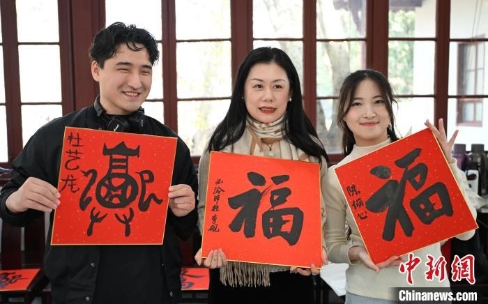 1月20日，外籍留學(xué)生和西泠印社社員李硯(中)展示各自創(chuàng)作的福貼。當(dāng)日，來自巴西、馬來西亞、加納、哈薩克斯坦的外籍留學(xué)生在浙江杭州西泠印社體驗福貼、春聯(lián)和篆刻，感受古老的中國傳統(tǒng)文化。中新社記者 王剛 攝