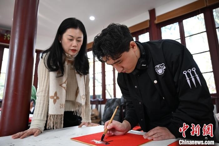 1月20日，外籍留學(xué)生在西泠印社社員李硯指導(dǎo)下寫福。當(dāng)日，來自巴西、馬來西亞、加納、哈薩克斯坦的外籍留學(xué)生在浙江杭州西泠印社體驗福貼、春聯(lián)和篆刻，感受古老的中國傳統(tǒng)文化。中新社記者 王剛 攝
