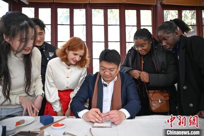 1月20日，篆刻家王臻向外籍留學(xué)生展示篆刻印章。當(dāng)日，來自巴西、馬來西亞、加納、哈薩克斯坦的外籍留學(xué)生在浙江杭州西泠印社體驗福貼、春聯(lián)和篆刻，感受古老的中國傳統(tǒng)文化。中新社記者 王剛 攝