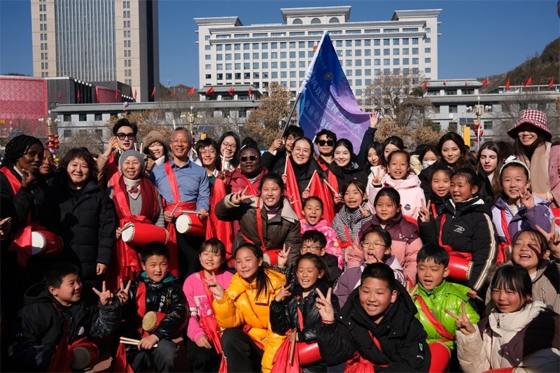 中外青年學(xué)子在安塞文化廣場觀看陜北腰鼓和大秧歌表演后合影留念，大家踏著鼓點(diǎn)共舞，翻飛的紅綢與躍動的身影交織，在黃土地廣場上繪出一幅生動的陜北民俗互動畫卷