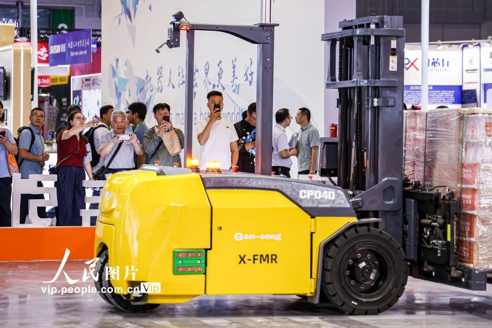 第24屆中國工博會現(xiàn)場，觀眾觀看叉取機(jī)器人作業(yè)演示。王初攝（人民圖片網(wǎng)）