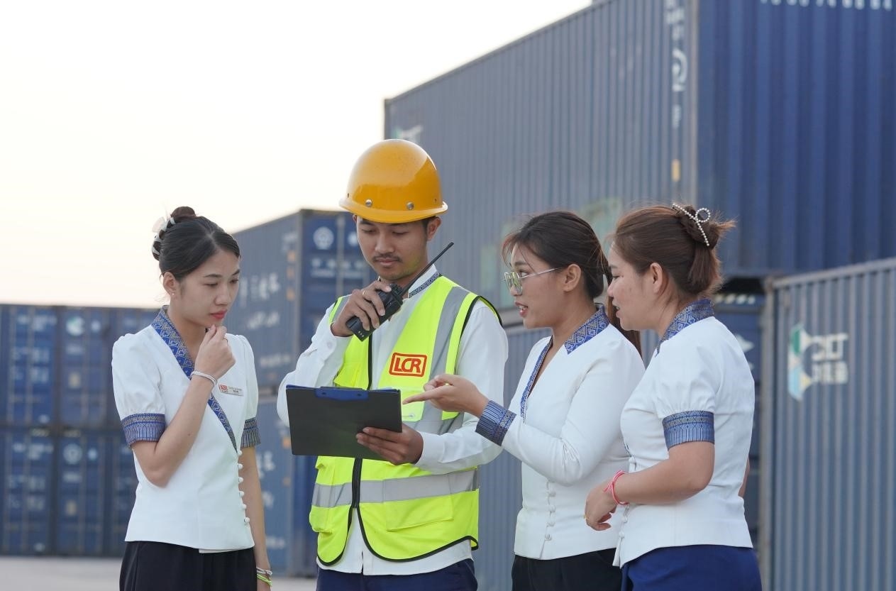 萬象南站貨運值班員陳尼啦（左一）與同事在一起討論工作。老中鐵路有限公司供圖