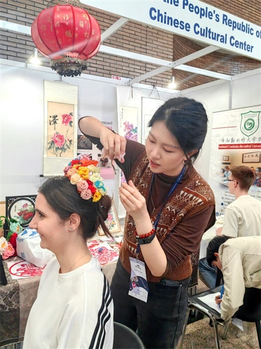 展覽正值羅馬尼亞迎春花節(jié)，國際中文教師志愿者潘婧穎向游客們介紹了國家非物質(zhì)文化遺產(chǎn)——福建泉州的簪花文化。布加勒斯特大學(xué)孔子學(xué)院供圖。