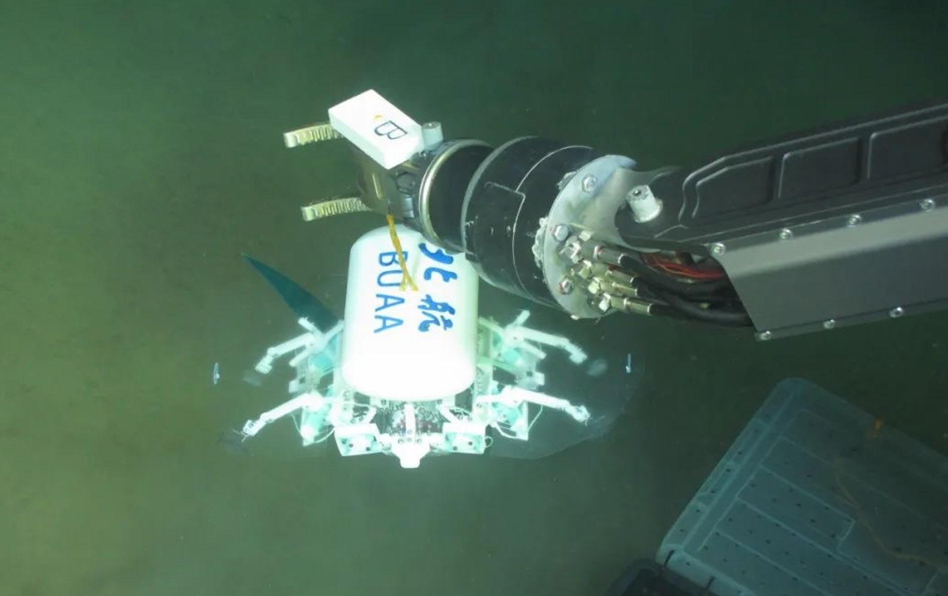 科研人員利用機(jī)械臂將北航深海小型機(jī)器人投于馬里亞納海溝。校方供圖