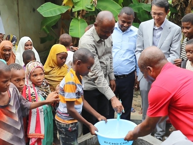 在日前舉行的安全供水工程揭牌儀式上，當?shù)匦∨笥言诠┧c接水。 施亮攝