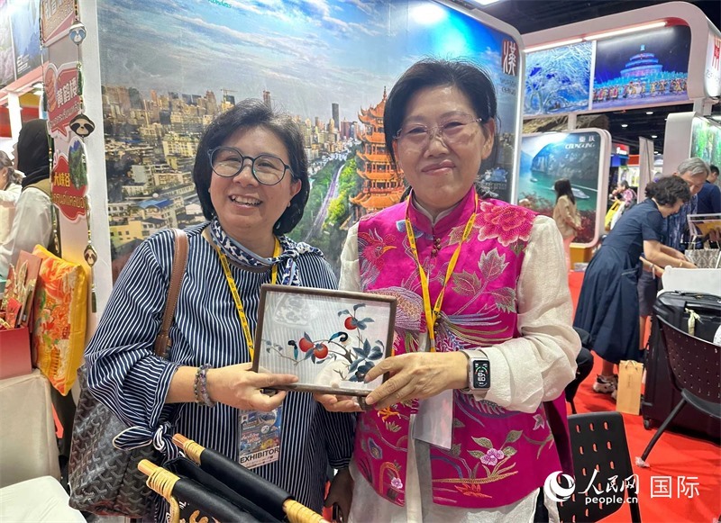 中國“大冶刺繡”傳承人劉小紅（右）參加泰國國際旅游展，向觀眾介紹中國非遺刺繡針法。人民網(wǎng)記者 簡承淵攝