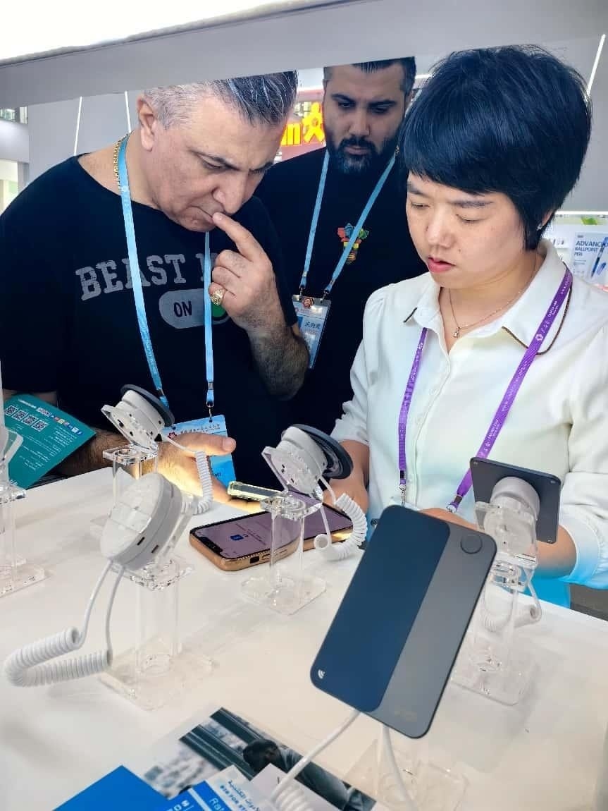 展臺(tái)工作人員向外商展示“AI TOP翻譯終端”。圖片來源：受訪者提供