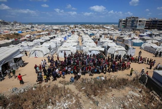 5月28日，人們?cè)诩由吵俏鞑康纳程犭y民營(yíng)等待領(lǐng)取救助食物。新華社發(fā)（里澤克·阿卜杜勒賈瓦德攝）